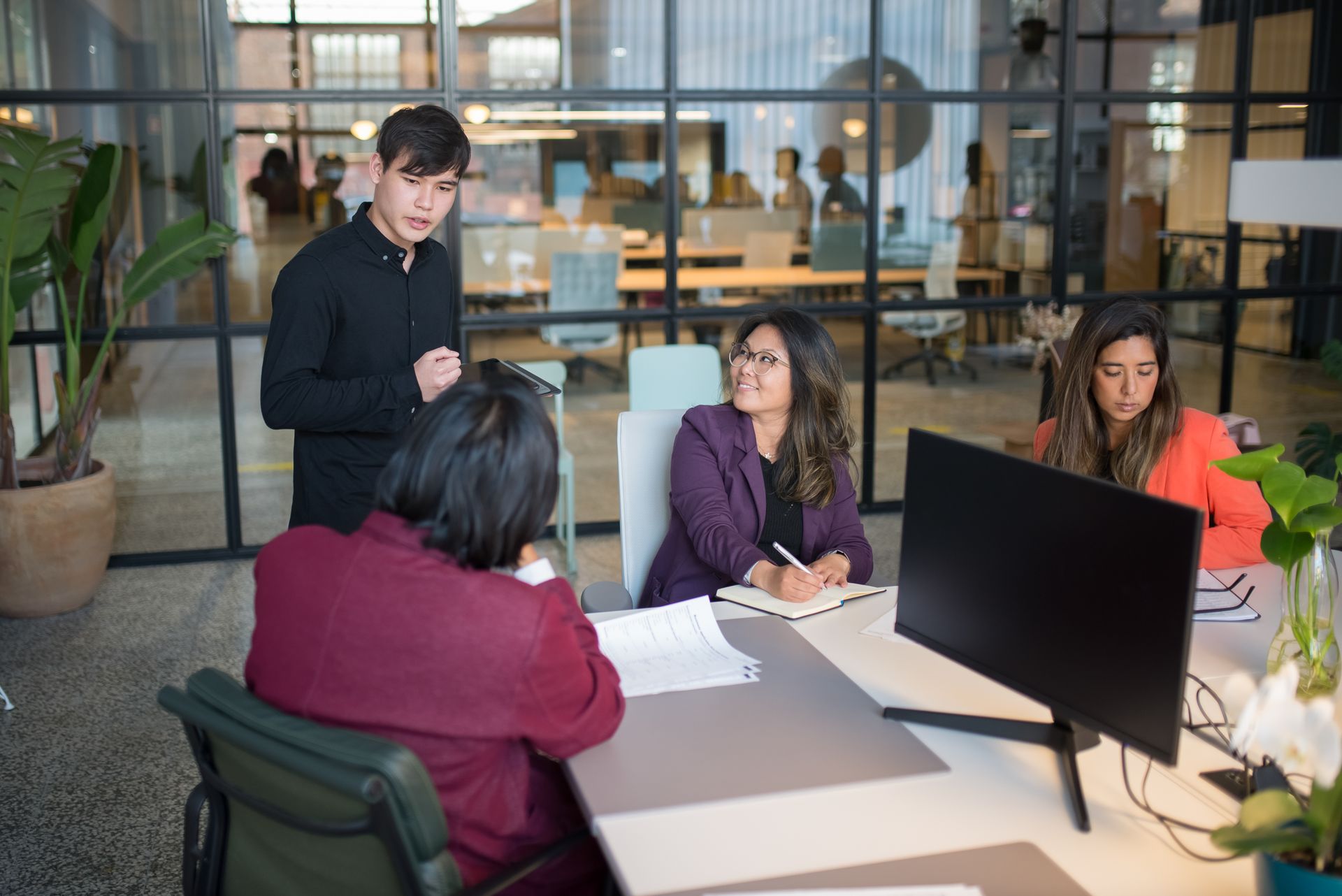 Adwella team members collaborating in a modern glass-walled office